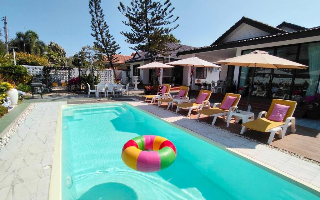 Celine Pool Villa's swimming pool, sun loungers and garden on a clear day
